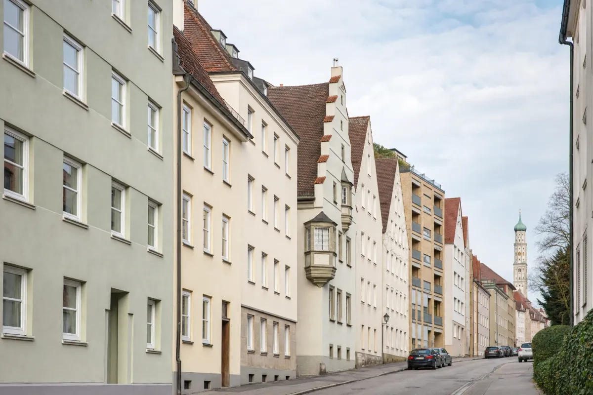 Wohnstraße in Augsburg: die für die Stadt typische Bebauung, im Hintergrund über den Dächern ein Wahrzeichen der Stadt.