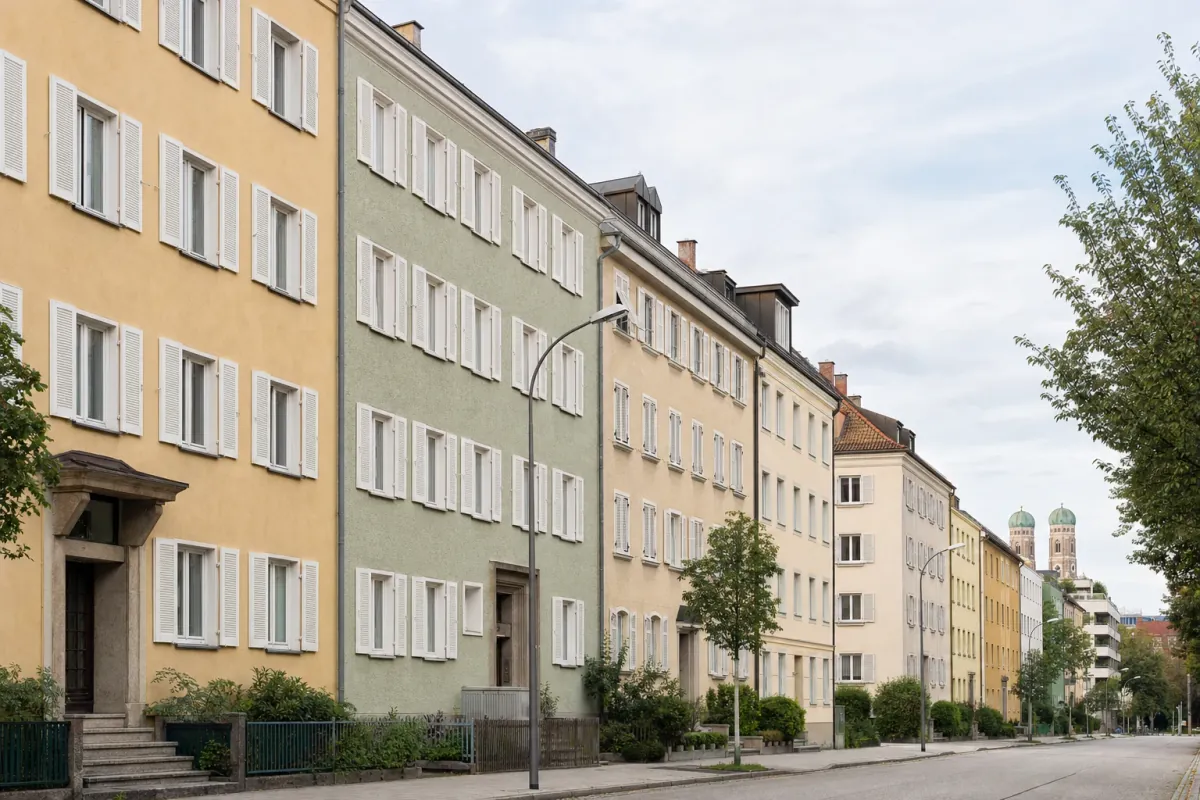 Wohnstraße in München: die für die Stadt typische Bebauung, im Hintergrund über den Dächern ein Wahrzeichen der Stadt.